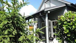 A house with a grey roof, white trim, and a porch with a potted plant. - Holiday Home in Rewal Near Baltic Beach (Rewal)