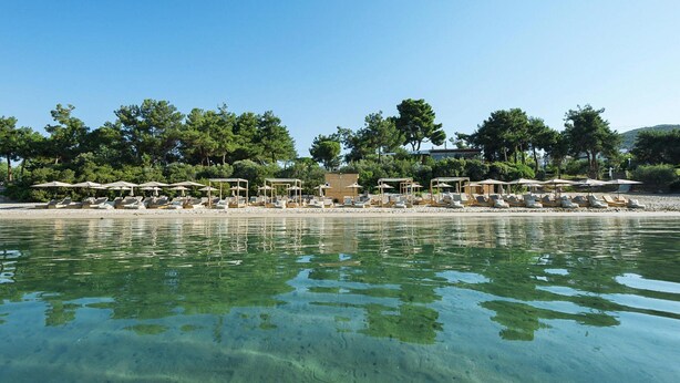 A beachside hotel with clear water, umbrellas, and lounge chairs. - Gerakini Holiday Home With a Balcony (Polygyros)