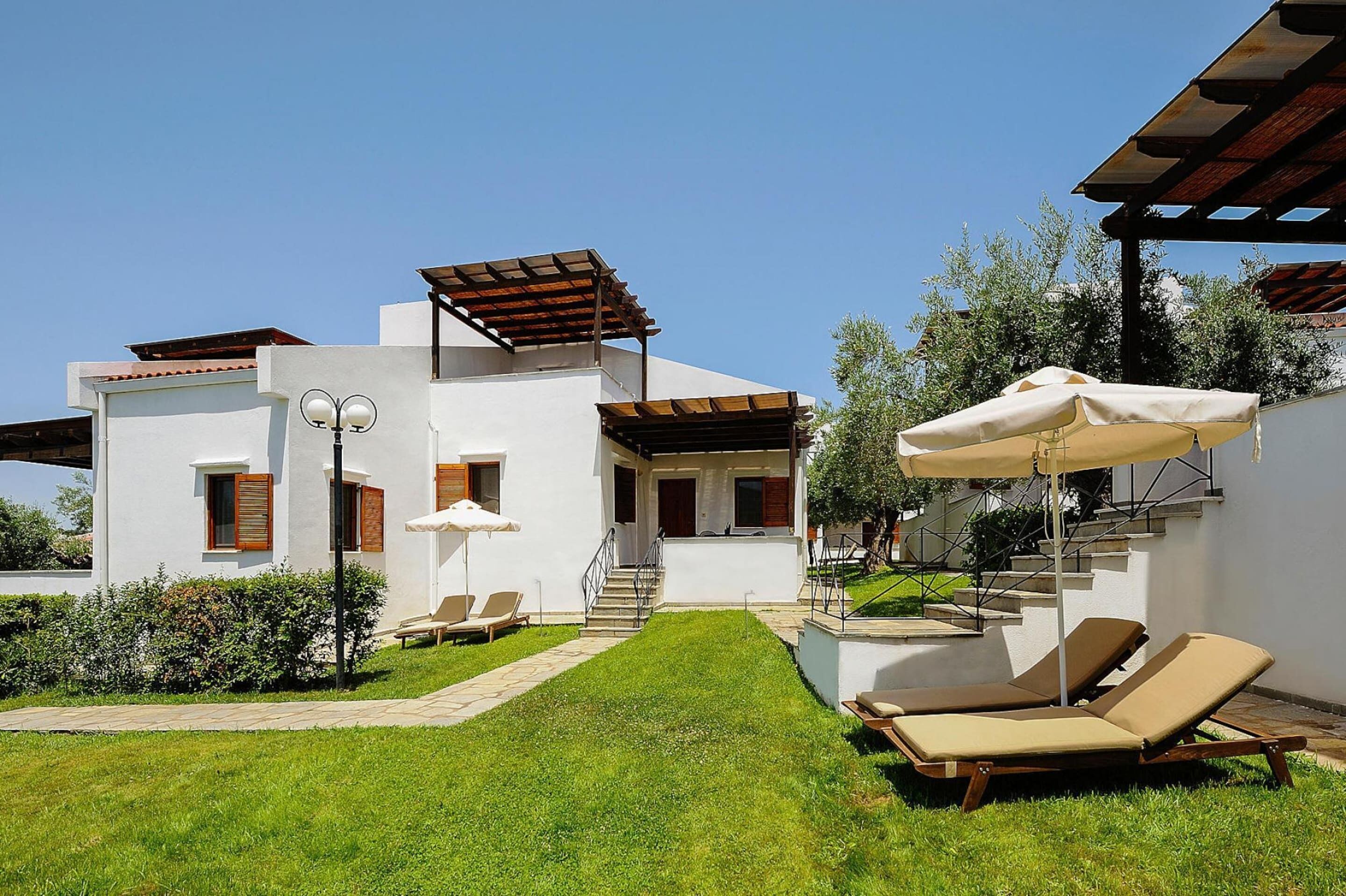Una casa moderna con un patio, mobiliario exterior y una escalera que lleva a la entrada.
