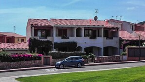 A two-story house with a red-tiled roof, a car parked in front, and a well-maintained lawn. - Apartment in Cannigione (Arzachena)