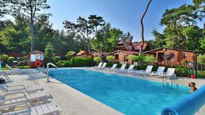 Une piscine avec des chaises longues et un chalet en bois en arrière-plan.