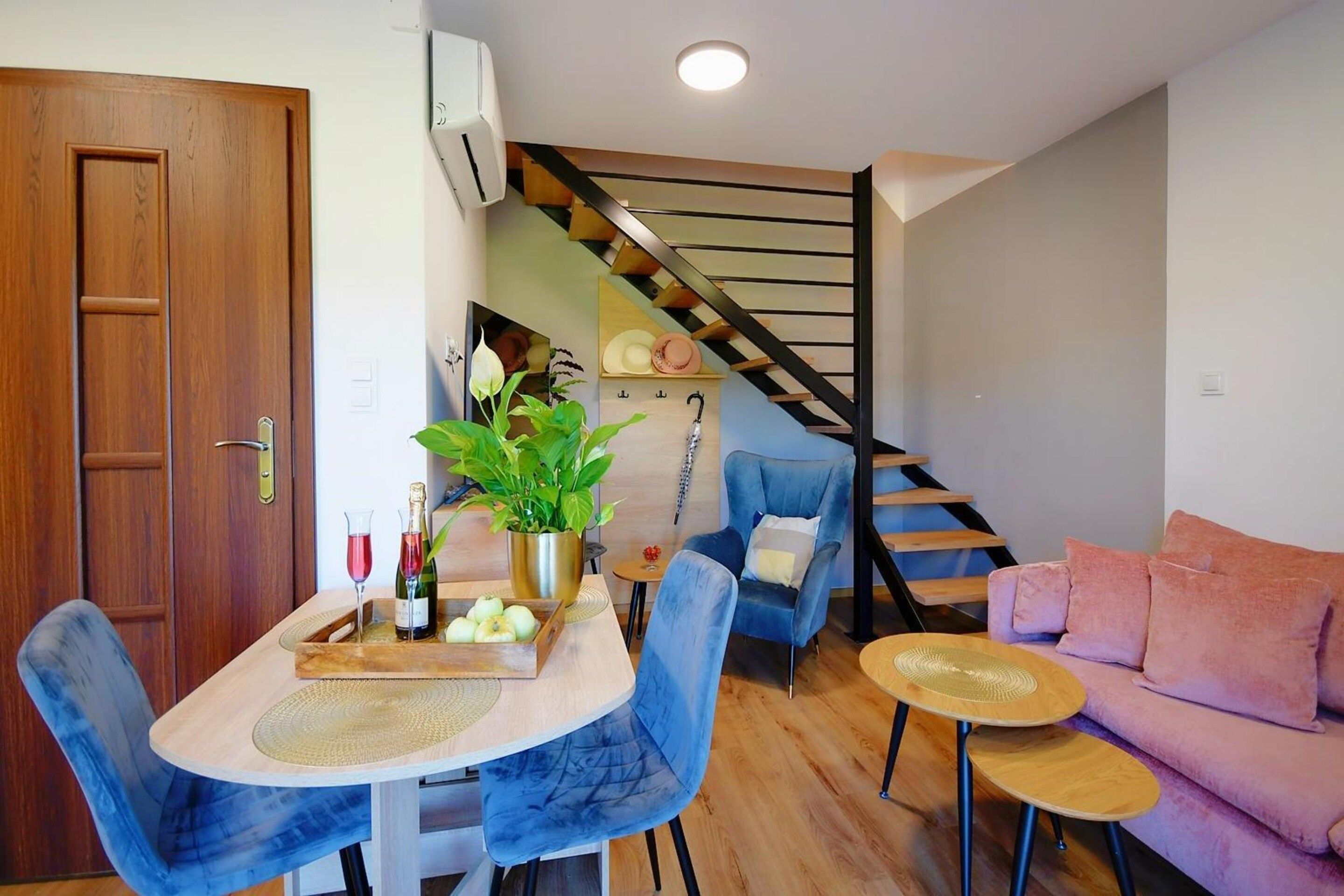 A compact living space with a dining area, a sofa, and a staircase.