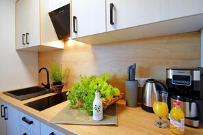 A modern kitchen with a black induction cooktop, a coffee maker, a kettle, and a fruit juice bottle. - Spacious Holiday Homes With Terraces, Mielenko (Mielno)
