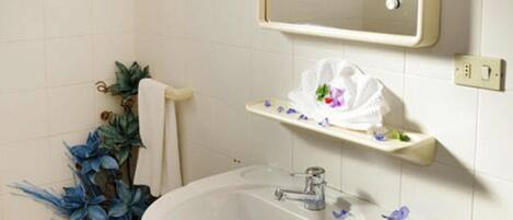 Un baño con lavamanos blanco, espejo y perchero para toallas.
