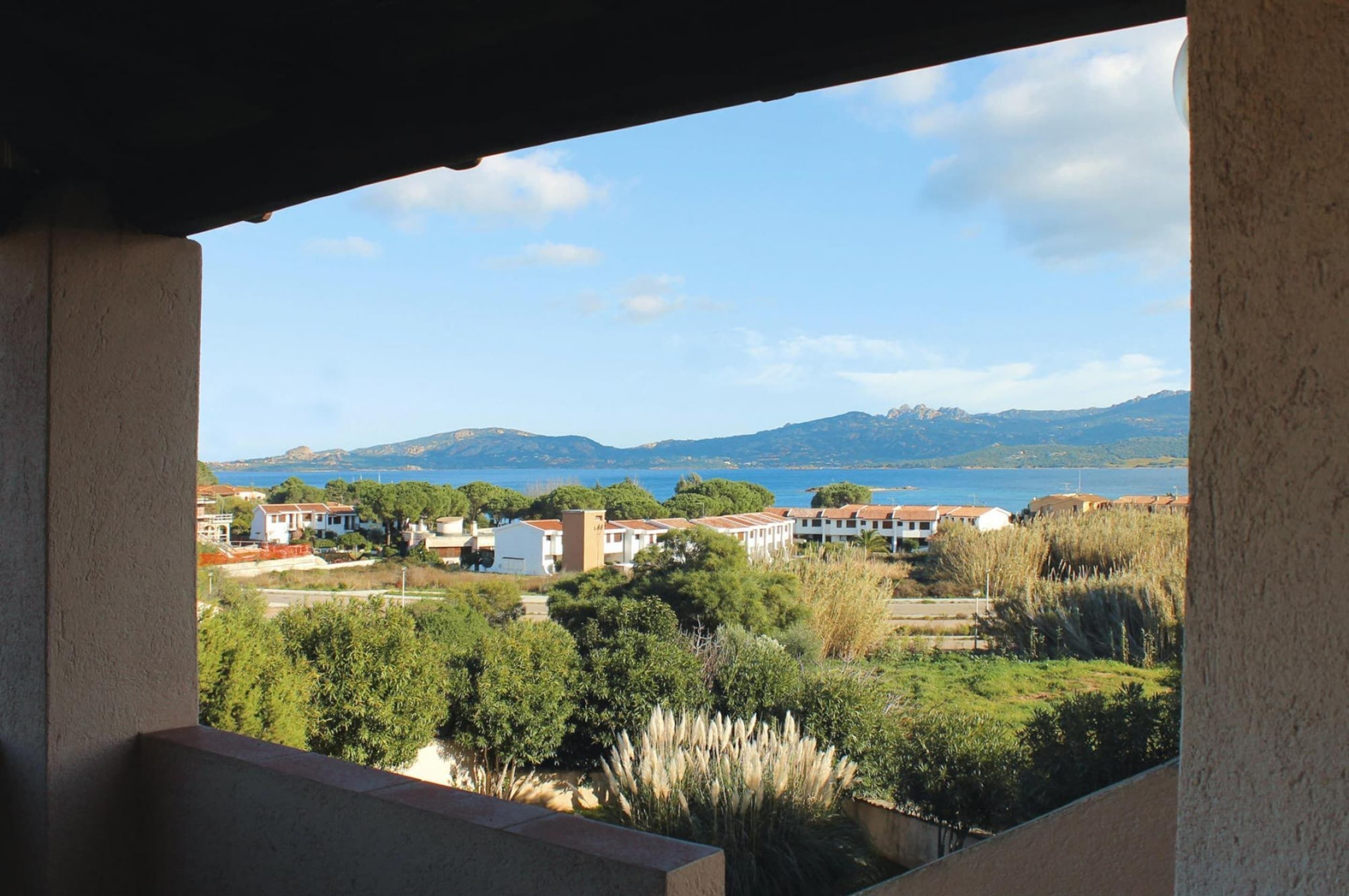 Un balcón con vistas a un pueblo costero, casas y montañas.