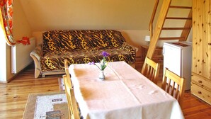 Een gezellige kamer met een bank, een tafel met een bloevas, een radiator en een houten ladder.