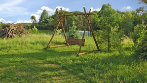 Een houten schommel in een grasveld met bomen op de achtergrond.