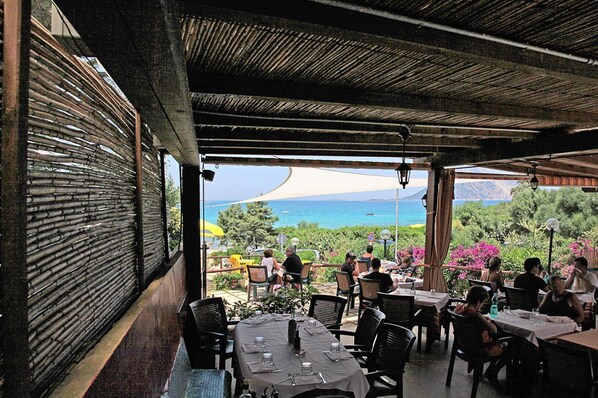 An outdoor restaurant with tables and chairs, overlooking a scenic view of the sea and mountains. - Comfortable House Near Lake Grevelinge (San Teodoro)