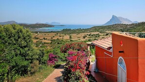 Paesaggio costiero con vista sul mare e montagne lontane.