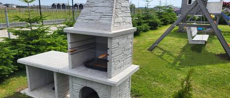 Una parrilla de piedra con chimenea, un banco de madera y un espacio cerrado pequeño para cocinar.