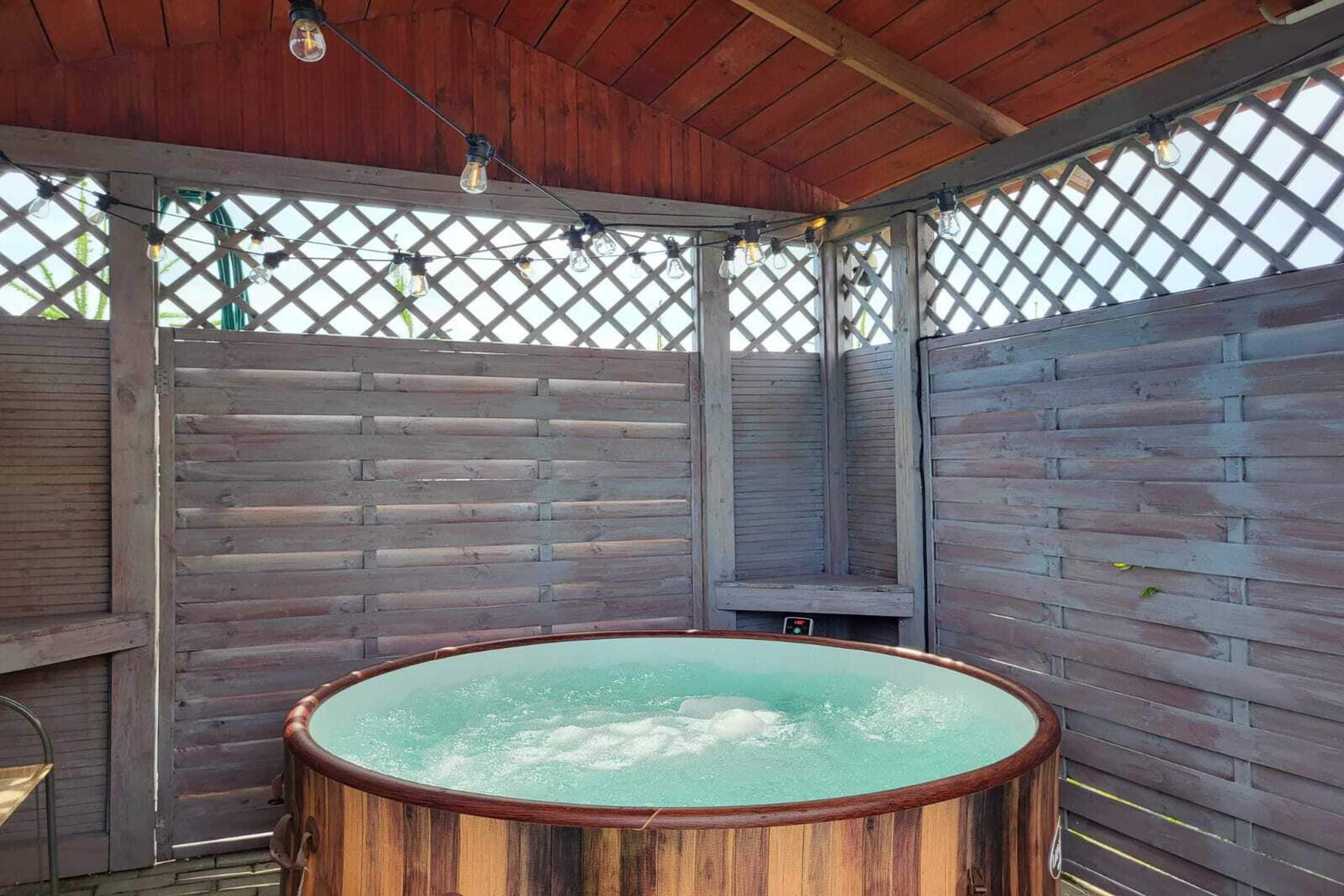An outdoor hot tub area with wooden walls and a lattice ceiling.