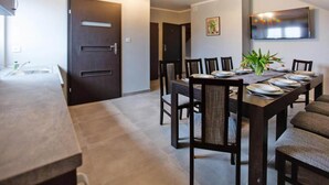 A dining area with a long table, chairs, and a TV mounted on the wall.