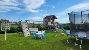 A playground with climbing structures, a slide, and a trampoline.