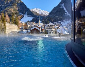 A pool with a view of a mountainous town, including a church and residential buildings. - Apartment in Ischgl With Sauna (Ischgl)