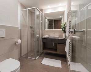 A modern bathroom with a glass-enclosed shower, a sink with a mirror above, and a toilet. - Apartment in Ischgl With Sauna (Ischgl)