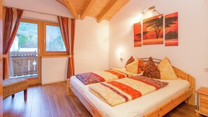 A bedroom with a wooden bed, a bench, and a window with curtains. - Chalet in Krimml Near Europe's Highest Waterfall (Krimml)