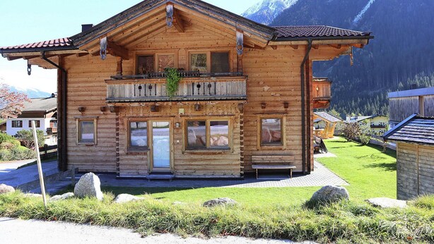A wooden chalet with a balcony, a front door, and a small garden area. - Chalet in Krimml Near Europe's Highest Waterfall (Krimml)
