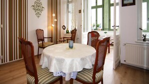 Une salle à manger avec une table ronde, six chaises en bois et une fenêtre donnant sur l’extérieur.