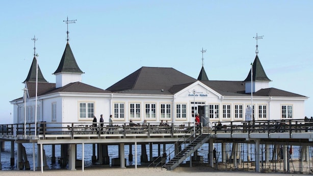 Un bâtiment blanc doté de trois tours, d’une jetée et d’une plage.