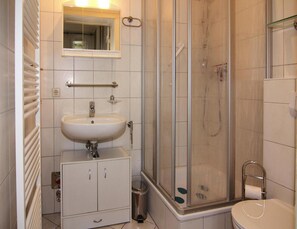 Een badkamer met een wit wastafelmeubel, spiegel en een douchecabine van glas.