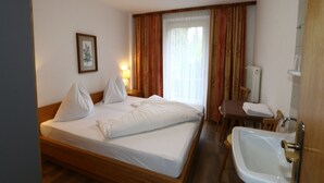 Une chambre d’hôtel comprenant un lit, un bureau, une chaise et une salle de bain avec un lavabo et un miroir.