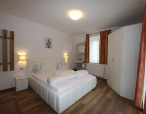 Une chambre à coucher avec un grand lit, des tables de chevet, une commode, un radiateur, un miroir et une armoire.