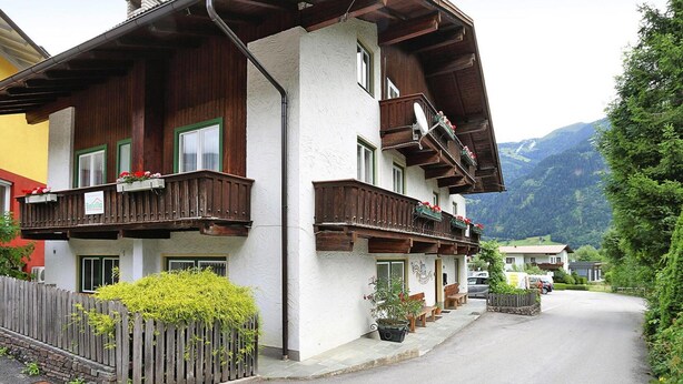 Un chalet traditionnel avec des balcons en bois, une façade blanche et un paysage de montagne en toile de fond.