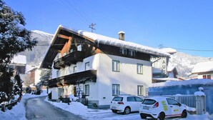 Un bâtiment à deux étages, doté d’un toit en pente, d’un balcon en bois et d’un sol recouvert de neige.