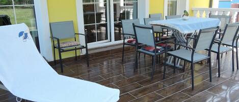 A sun lounger, outdoor dining area, and a view of a building in the background.