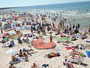 Una spiaggia affollata con molte persone, ombrelloni e lettini.