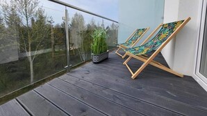 A balcony with two wooden lounge chairs and a potted plant. - Comfortable Holiday Apartment Close to the sea (Mielno)