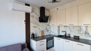 A modern kitchen with white cabinets, a black stove, and a marble backsplash. - Comfortable Holiday Apartment Close to the sea (Mielno)