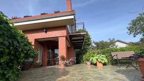Une maison en briques avec un patio carrelé, un vélo et des plantes en pot.