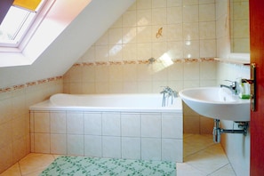 Ein Badezimmer mit Badewanne, Waschbecken und Fenster.