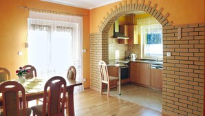 Una cucina con mobili in legno, una parete di fondo in mattoni e un'area pranzo con tavolo e sedie.