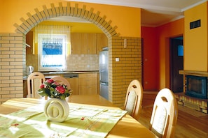 Ein Essbereich mit einer Ziegelbogenarchitektur, einem Tisch mit floraler Dekoration und einem Fernseher im Hintergrund.