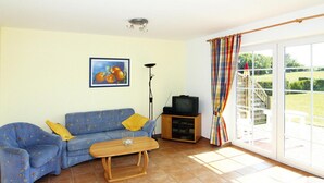 Un salon avec un canapé, une table basse, un téléviseur et un tableau accroché au mur.