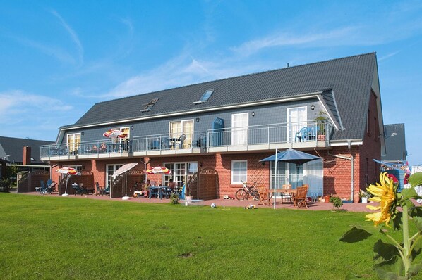 A two-story building with a balcony, outdoor seating, and a lawn. - Ferienanlage Schuldt, Behrensdorf (Behrensdorf)