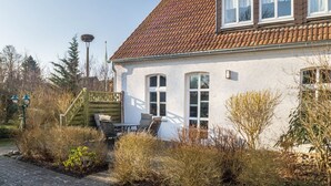 Ein Haus mit Ziegeldach, weißen Außenwänden und einer Veranda mit Tisch und Stühlen.