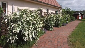 Ein Haus mit rotem Dach, weißen Außenwänden und einem Ziegelweg, der zum Eingang führt.