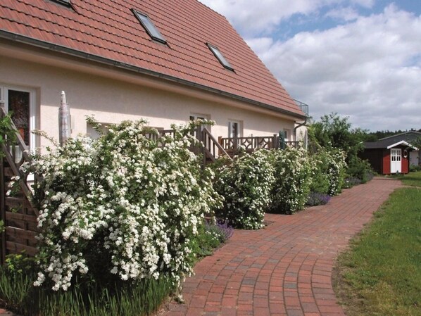 A house with a red roof, white exterior walls, and a brick pathway leading to the entrance.