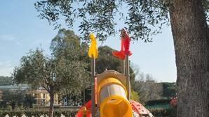 A playground with a slide and climbing structures, surrounded by trees and a building in the background. - Village Mobile Home in Rebi (Imperia)
