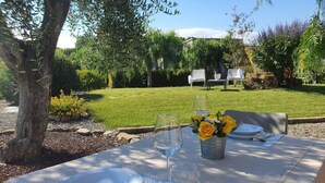 An outdoor dining area with a table set for two, surrounded by greenery and a lawn. - Village Mobile Home in Rebi (Imperia)