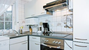 A modern kitchen with white cabinets, stainless steel appliances, and a window providing natural light.