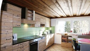 A kitchen with wooden cabinetry, a tiled backsplash, a built-in oven, and a window with a view of trees.