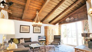 A living room with a wooden ceiling, a sofa, a coffee table, a television, and a fireplace.
