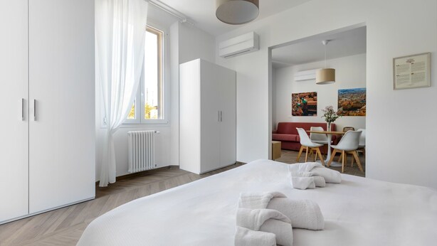 Ein modernes Hotelzimmer mit einem großen Bett, einem Essbereich und Blick auf die Stadt.