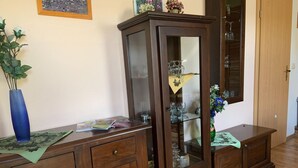 A wooden cabinet with glass doors, a vase with flowers, and a blue vase on a table. - Ferienwohnung im Luckaitztal Gosda (Luckaitztal)
