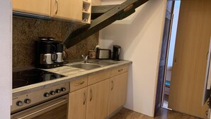 A compact kitchen with a stove, sink, and countertop appliances. - Ferienwohnung im Luckaitztal Gosda (Luckaitztal)