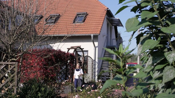 A house with a red-tiled roof, a wooden gate, and a garden with pink flowers. - Ferienwohnung im Luckaitztal Gosda (Luckaitztal)